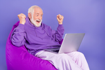 Portrait of handsome bearded elderly retired trendy lucky man pensioner using laptop rejoice...