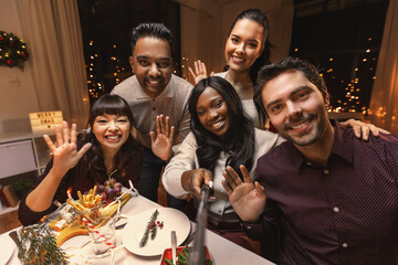 holidays, friendship and celebration concept - multiethnic group of happy friends having christmas dinner at home and taking selfie