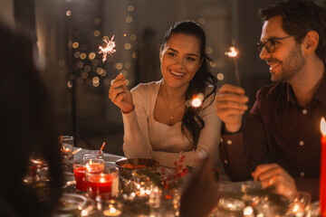 holidays and celebration concept - multiethnic group of happy friends with sparklers having...