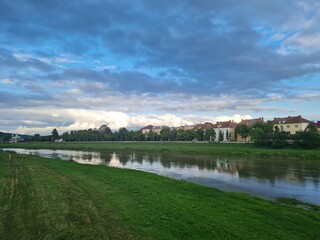 Natural beauty of blue sky and calm water of river in Mukachevo, Ukraine. Beautiful landscape with river and houses at sunset. Scenic view of the old town embankment on a cloudy summer day at dusk.