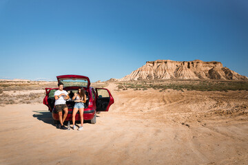 One woman and one man eating and chatting in a car while travelling at Bardenas Reales desert,...