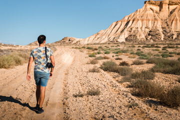 Fototapeta premium Young man with a camera in Bardenas Reales desert, Navarra, Basque Country.