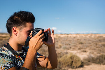 Young man with a camera in Bardenas Reales desert, Navarra, Basque Country.