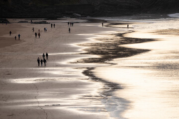 people walking along Sopelana beach in Vizcaya at sunset
