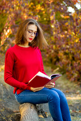 Lady in red sweater reads in nature. Girl and book