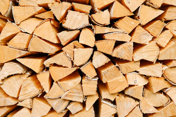 A woodpile of firewood lies in a pile, chopped for burning in the oven.Preparation for winter. A pile of logs for firewood. Background with firewood.Buying and selling firewood for winter