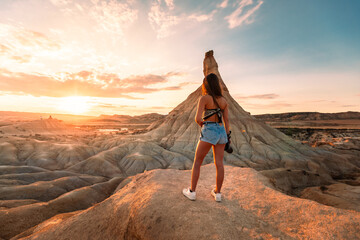 Young caucasian woman with a camera in front of Castildetierra formation at Bardenas Reales desert, Navarra, Basque Country.