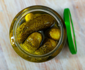 Glass jar with pickled cucumbers on a wooden table. High quality photo