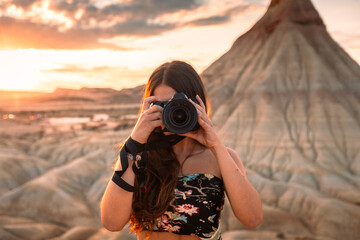Young caucasian woman with a camera in front of Castildetierra formation at Bardenas Reales desert,...