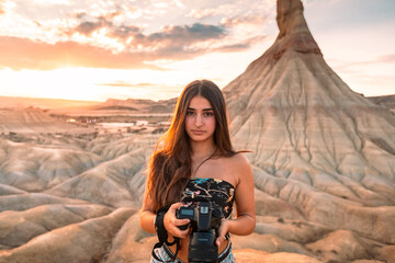 Young caucasian woman with a camera in front of Castildetierra formation at Bardenas Reales desert,...