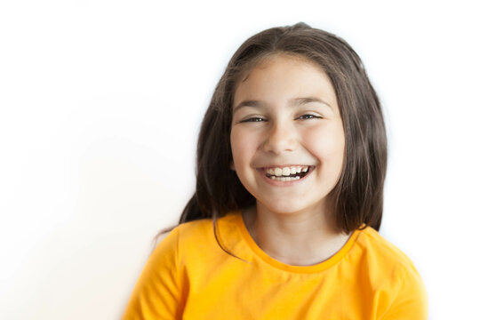 Happy positive smiling child girl with a long hair in yellow T-shirt isolated on white background