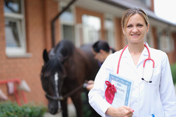 Woman doctor holding certificate with genetic examination of purebred horse in stable