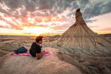 Fototapeta na wymiar Young caucasian man in front of Castildetierra natural monument while sunset at Bardenas Reales desert, Navarra, Basque Country.