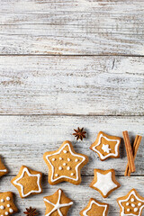Border of Christmas gingerbreads in the shape of a star with patterns of glaze and spices on a white wooden background.