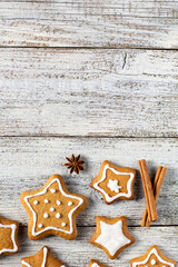 Border of Christmas gingerbreads in the shape of a star with patterns of glaze and spices on a white wooden background.