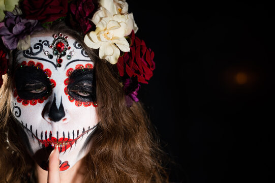 Woman in santa muerte makeup on a black background. Girl wearing traditional mexican holy death costume for halloween. Copy space