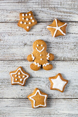 Christmas gingerbreads in the shape of a star and man with patterns of glaze and spices on a white wooden background.