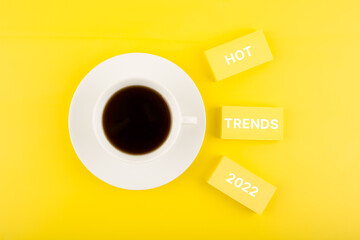 Hot trends 2022 written on rectangles next to cup of coffee on bright yellow background