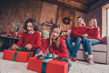 Full size photo of excited little kid open gift box mom an dad sit couch admire enjoy holiday together indoors