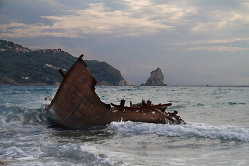 Waves splashing on the rusty wreck of a broken, stranded fishing boat