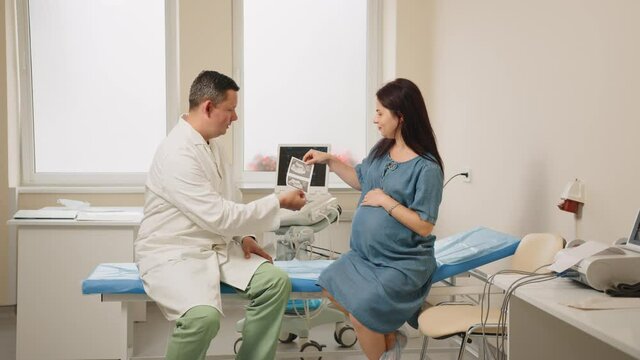 Doctor giving images after ultrasound to pregnant woman