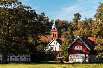 Fototapeta na wymiar Juodkrante, Lithuania - 10th October 2021: church and other historical buildings surrounded by trees in morning light