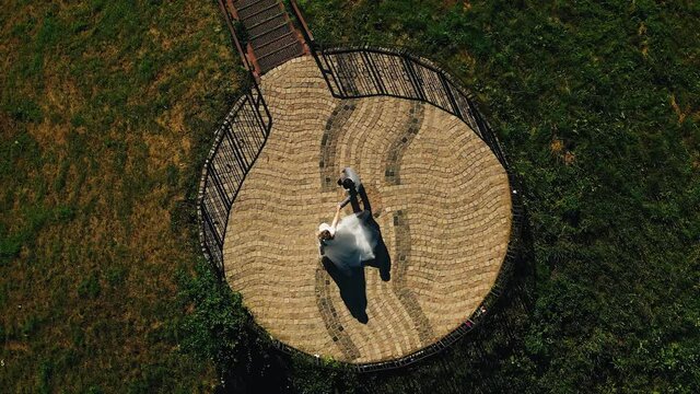 A couple of newlyweds in love are dancing on a large stone platform. Aerial photography from above