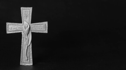 Isolated ornate religious cross with a flower on a dark background. Moment of grief at the end of a...