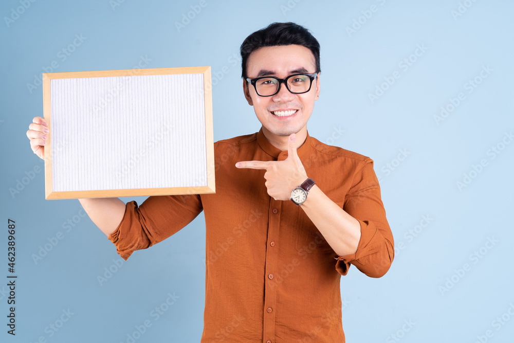 Sticker young asian man holding white board on blue background