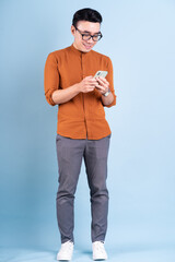 Young Asian man using smartphone on blue background