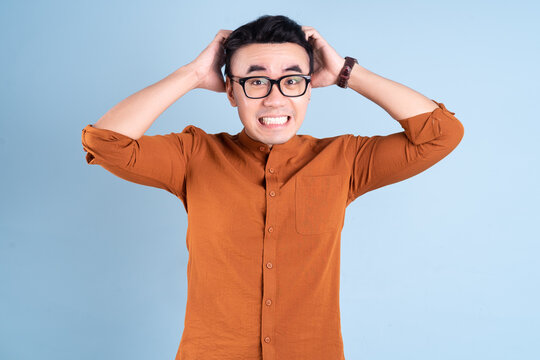 Young Asian businessman posing on blue background