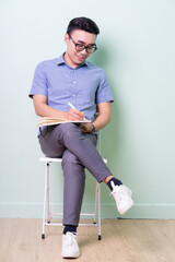 Young Asian buisnessman sitting on chair in green background