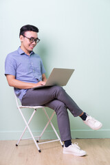 Young Asian buisnessman sitting on chair in green background