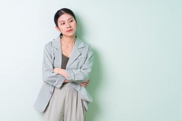 Young Asian businesswoman wearing green suit on green background