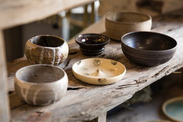 Handmade empty clay dishes composition on a wooden shelf in a shop