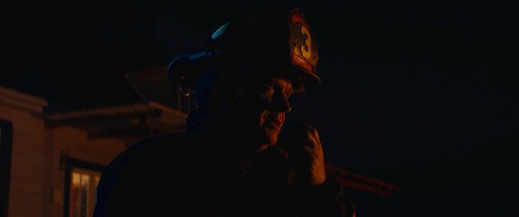 Firefighter chief talking on CB radio and giving orders to his crew, fireman fighting house fire in a neighborhood