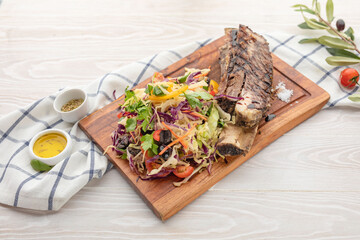 ruby on a bone with arugula and vegetable side dish on a wooden plaque