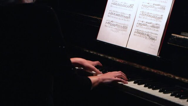 a girl in the shadow plays the piano in the theater