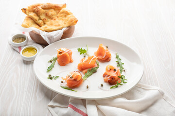 red fish on a white plate with flatbread and cheese