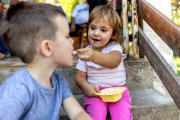 Cropped shot of a cute little girl sharing a dish of popcorn with her big brother. Brother and...