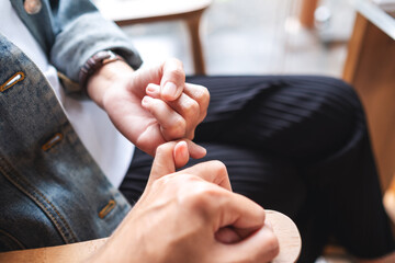 A man and a woman hooking each other little finger for swear and promise