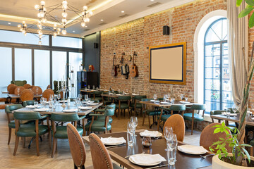 Interior of a modern hotel restaurant with old instruments hanging on the brick wall as a decoration