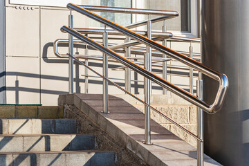 A ramp and metal railings at the entrance to the residential building for the convenience of people with disabilities and the elderly.