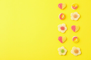 Gummy candies on yellow background, space for text