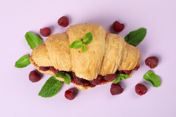 Croissant with raspberry jam on purple ​background