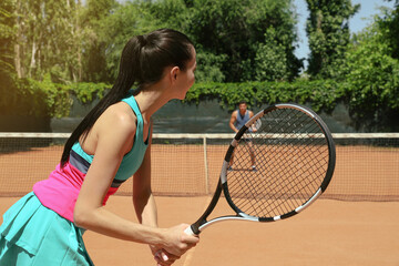 Couple playing tennis on court during sunny day
