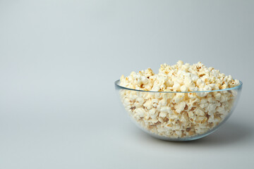 Glass bowl with popcorn on light gray background