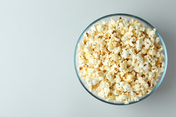 Glass bowl with popcorn on light gray background