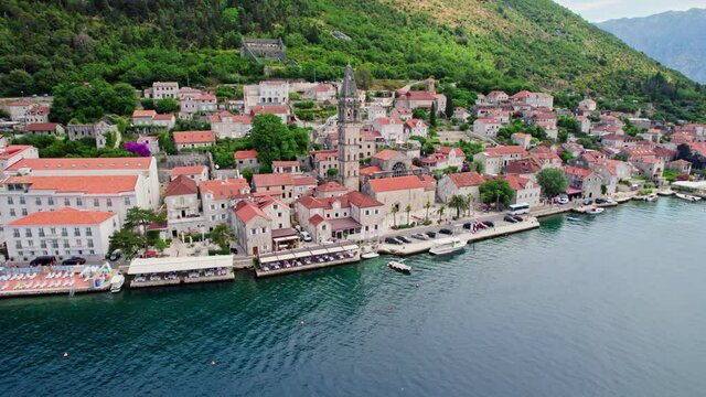 Flying over the old town of Perast, Kotor bay, Montenegro. Old medieval town with red roofs on the coast of Adriatic sea. Aerial shot