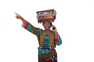 woman with traditional loincloth on her head speaking on mobile phone and pointing finger aside smiling.